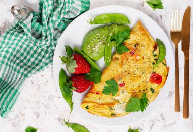 Omelette with tomatoes, feta cheese and avocado on white plate. Top view, flat lay