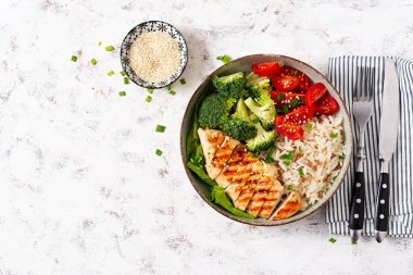 Delicious buddha bowl with grilled chicken, fresh vegetables and rice on a light background. Top view, above