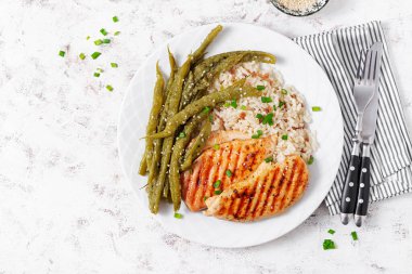 Chicken fillet cooked on a grill and garnish of rice, green beans. Top view