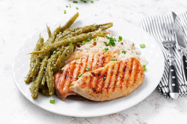 Chicken fillet cooked on a grill and garnish of rice, green beans.