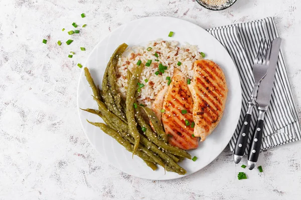 Chicken fillet cooked on a grill and garnish of rice, green beans. Top view