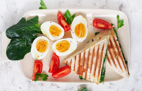 Fresh tortilla wraps with spinach and cheese on light background .  Healthy food concept. Vegetarian food. Top view, overhead