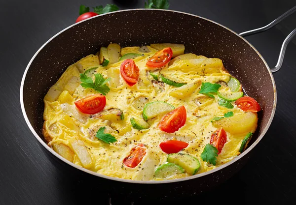 Omelette with tomatoes,  zucchini and potatoes on dark background. Healthy diet food for breakfast. Tasty morning food.