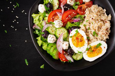 Healthy breakfast. Greek inspired savory oatmeal with fresh cucumber, tomatoes, olives, lettuce, mozzarella cheese and boiled egg. Top view