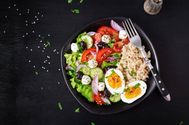 Healthy breakfast. Greek inspired savory oatmeal with fresh cucumber, tomatoes, olives, lettuce, mozzarella cheese and boiled egg. Top view