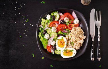 Healthy breakfast. Greek inspired savory oatmeal with fresh cucumber, tomatoes, olives, lettuce, mozzarella cheese and boiled egg. Top view