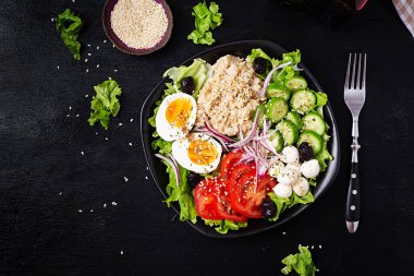 Healthy breakfast. Savory oatmeal with fresh cucumber, tomatoes, olives, lettuce, mozzarella cheese and boiled egg. Top view