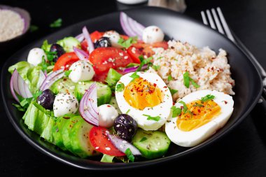 Healthy breakfast. Greek inspired savory oatmeal with fresh cucumber, tomatoes, olives, lettuce, mozzarella cheese and boiled egg. Top view
