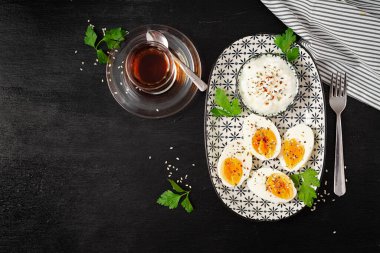 Boiled eggs with yogurt, peppers, parsley and cup tea. Healthy diet food for breakfast. Top view, flat lay.