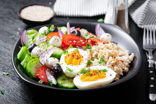 Healthy breakfast. Greek inspired savory oatmeal with fresh cucumber, tomatoes, olives, lettuce, mozzarella cheese and boiled egg. Top view