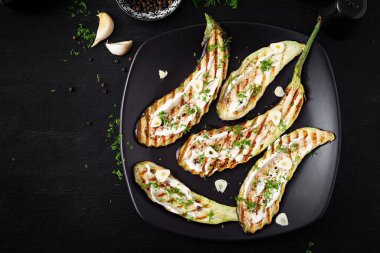 Grilled eggplant and yogurt sauce  on a black background. Baked aubergine. Top view, above