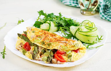 Keto kahvaltısı. Tavuk fileto, domates ve beyaz ahşap masada kuşkonmaz ile omlet. İtalyan omleti. Keto, ketojenik öğle yemeği..