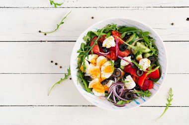 Kahvaltıda. Yunan salatası ve haşlanmış yumurta. Domates, salatalık, zeytin, roka ve krem peynirli taze sebze salatası. Moda yemekler. Üst manzara, düz uzanma