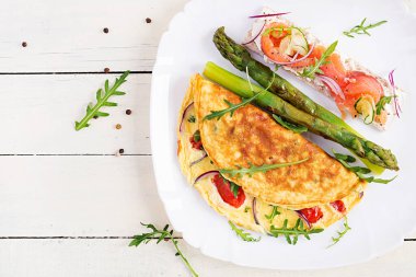 Ketojenik kahvaltı. Domatesli omlet, kırmızı soğan, somonlu sandviç ve kızarmış kuşkonmaz. İtalyan omleti. Keto, ketojenik öğle yemeği. Üst manzara, düz uzanma
