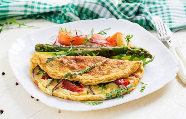 Ketojenik kahvaltı. Domatesli omlet, kırmızı soğan, somonlu sandviç ve kızarmış kuşkonmaz. İtalyan omleti. Keto, ketojenik öğle yemeği..