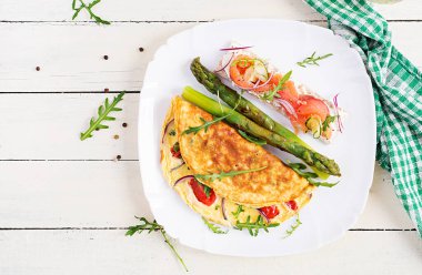 Ketojenik kahvaltı. Domatesli omlet, kırmızı soğan, somonlu sandviç ve kızarmış kuşkonmaz. İtalyan omleti. Keto, ketojenik öğle yemeği. Üst manzara, düz uzanma