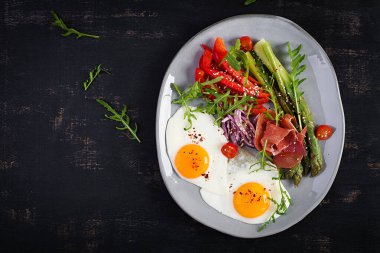 Keto kahvaltısı. Kızarmış yumurtalı, jambonlu ya da jambonlu kuşkonmaz. Ketogenik diyet. Sağlıklı yiyecekler. Üst manzara, düz uzanma