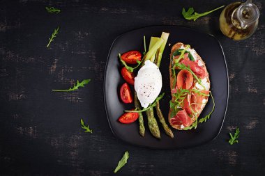 Keto kahvaltısı. Kavrulmuş yumurtalı kuşkonmaz ve jambonlu tost. Ketogenik diyet. Sağlıklı yiyecekler. Üst manzara, düz uzanma