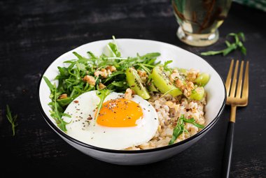 Kahvaltı yulaf lapası, kızarmış yumurta, kivi, roka ve keten tohumu. Kolesterolü düşürmek için sağlıklı kahvaltı..