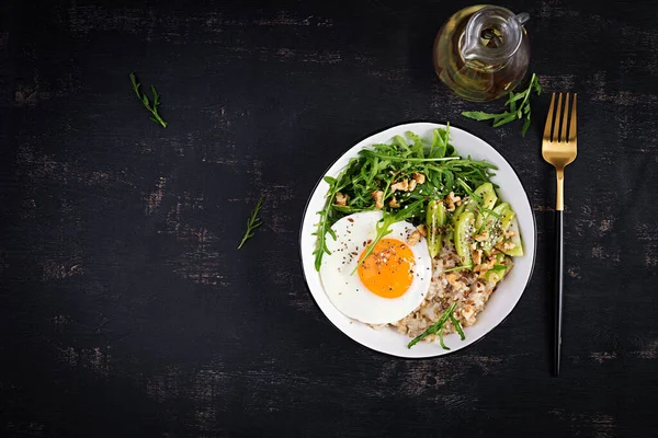 stock image Breakfast oatmeal porridge with roasted eggs, kiwi, arugula and flax seeds. Healthy breakfast to lower cholesterol. Top view, flat lay