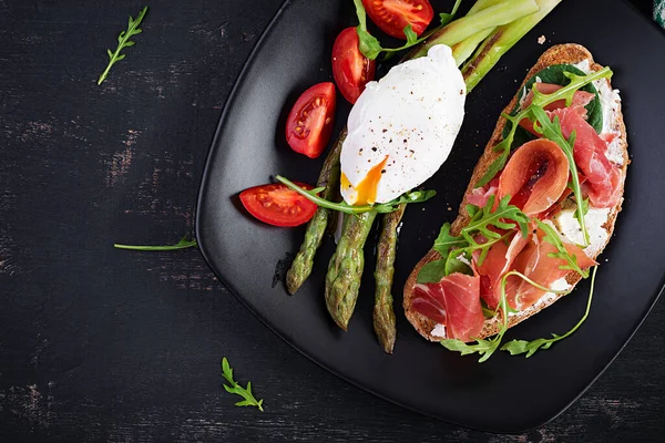 Keto kahvaltısı. Kavrulmuş yumurtalı kuşkonmaz ve jambonlu tost. Ketogenik diyet. Sağlıklı yiyecekler. Üst manzara, düz uzanma