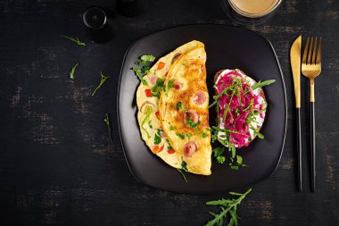 Kahvaltıda. Sosisli omlet, tatlı biber ve marine edilmiş kırmızı soğanlı sandviç. Frittata - İtalyan omleti. Üst görünüm