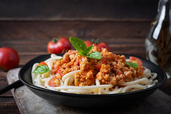 Spagetti makarna ve domates sosu ve ahşap arka planda tavuk kıyması. Makarna bolonez.