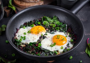 Kahvaltıda. Yeşil pancar yapraklı kızarmış yumurta, sarımsak, biber ve tavada yeşil soğan..