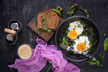 Kahvaltıda. Yeşil pancar yapraklı kızarmış yumurta, sarımsak, biber ve tavada yeşil soğan. Üst manzara, düz uzanma