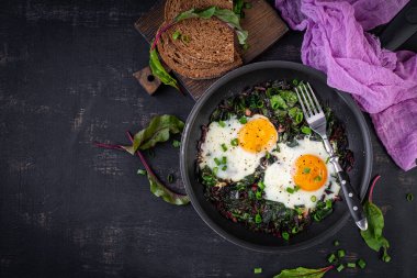 Kahvaltıda. Yeşil pancar yapraklı kızarmış yumurta, sarımsak, biber ve tavada yeşil soğan. Üst manzara, düz uzanma