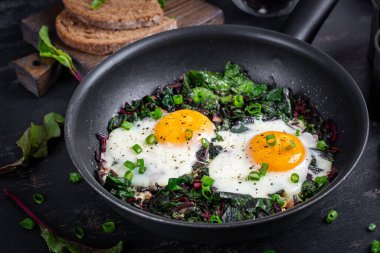 Kahvaltıda. Yeşil pancar yapraklı kızarmış yumurta, sarımsak, biber ve tavada yeşil soğan..