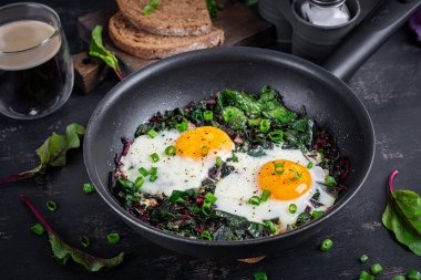 Kahvaltıda. Yeşil pancar yapraklı kızarmış yumurta, sarımsak, biber ve tavada yeşil soğan..