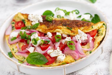 Domatesli omlet, peynir ve beyaz tabakta kırmızı soğan. Frittata - İtalyan omleti.