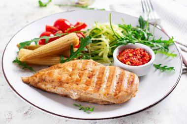 Healthy keto, ketogenic lunch with grilled chicken  breast, fillet and  salad of arugula, onion, boiled corn, cucumber and tomato. Roasted chicken meat and salad. clipart