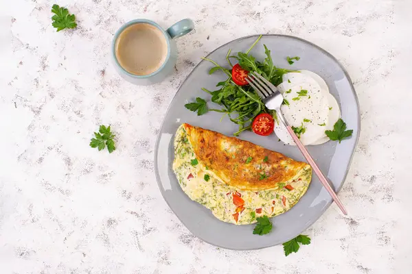 Domatesli omlet ve tabakta salata. Frittata - İtalyan omleti. Keto, ketojenik diyet. Üst görünüm