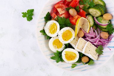 Kahvaltıda. Yunan salatası ve haşlanmış yumurta. Domates, salatalık, zeytin, roka ve peynirli taze sebze salatası. Moda yemekler. Üst manzara, düz uzanma