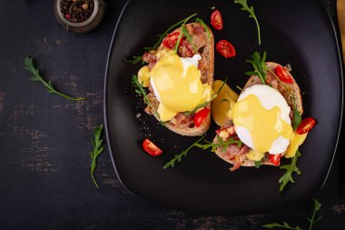 Kahvaltıda. Jambonlu sandviç, haşlanmış yumurta, soğan ve koyu arkaplanda roka. Üst görünüm