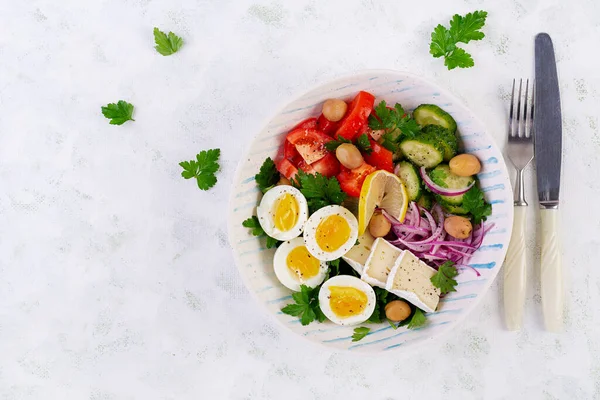 Kahvaltıda. Yunan salatası ve haşlanmış yumurta. Domates, salatalık, zeytin, roka ve peynirli taze sebze salatası. Moda yemekler. Üst manzara, düz uzanma