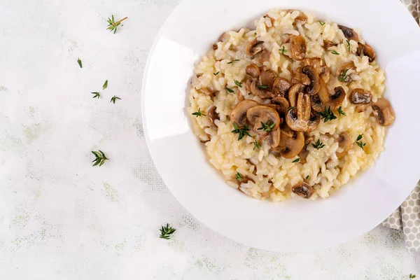 Dish with delicious risotto with mushrooms in plate. Rice porridge with fungus and tmyne. Hot dish, italian cuisine. Top view