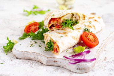 Izgara tortilla, tavuklu ve taze sebzeli beyaz ahşap tahtada. Tavuk dürüm. Meksika yemeği. Sağlıklı gıda konsepti.