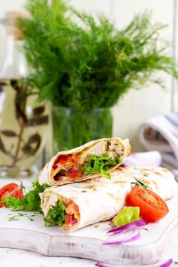 Izgara tortilla, tavuklu ve taze sebzeli beyaz ahşap tahtada. Tavuk dürüm. Meksika yemeği. Sağlıklı gıda konsepti.