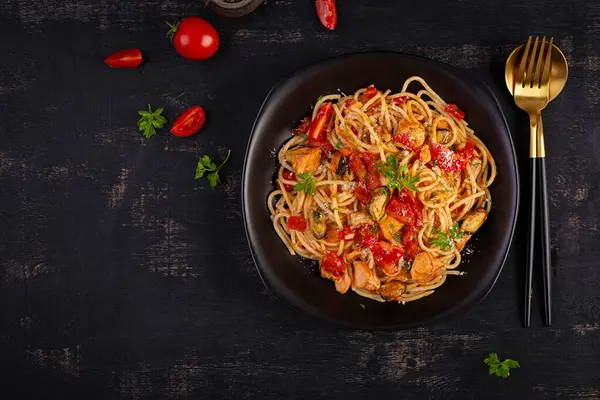Classic italian pasta spaghetti marinara with mussels and salmon on dark table. Spaghetti pasta with sauce marinara. Top view, overhead