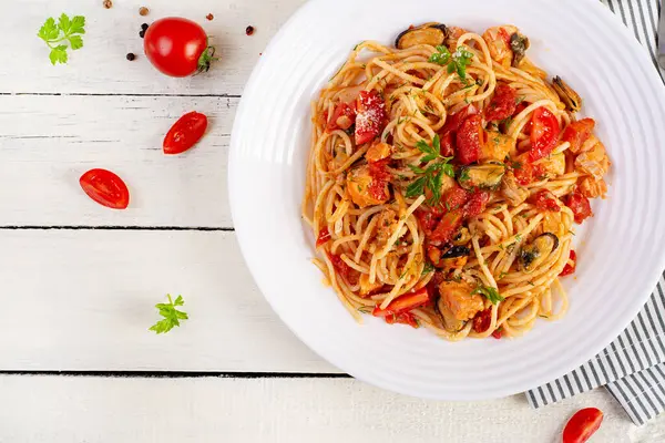 Classic italian pasta spaghetti marinara with mussels and salmon on white table. Spaghetti pasta with sauce marinara. Top view, overhead