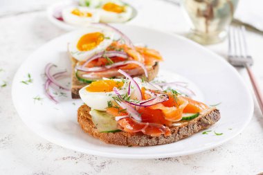 Somonlu tost, haşlanmış yumurta, salatalık ve krem peynirli beyaz tabak. Sağlıklı beslenme, kahvaltı. Keto diyet yemeği. Lezzetli yemek..