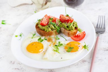 Keto kahvaltısı. Kızarmış yumurta ve tost, yanında guacamole ve domates..