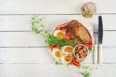 İngiliz kahvaltısı. Haşlanmış yumurta, fasulye, tost ve yeşil otlar. Üst manzara, düz uzanma