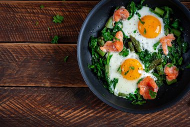 Keto kahvaltısı. Kuşkonmaz, ıspanak ve somonlu sahanda yumurta. Üst manzara, düz uzanma