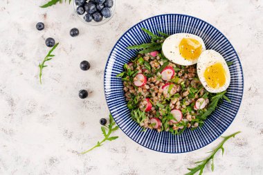 Sağlıklı kahvaltı. Haşlanmış yumurta, turp ve yeşil otlu karabuğday lapası. Karabuğday tabbouleh. Üst görünüm
