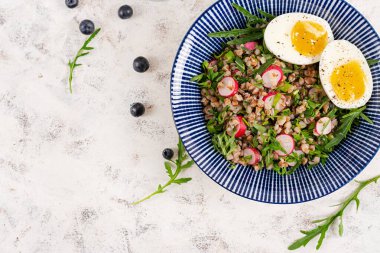 Sağlıklı kahvaltı. Haşlanmış yumurta, turp ve yeşil otlu karabuğday lapası. Karabuğday tabbouleh. Üst görünüm