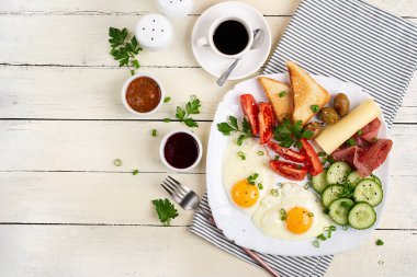 English breakfast - fried egg, salami, cheese, tomatoes, cucumbers and toast. Top view